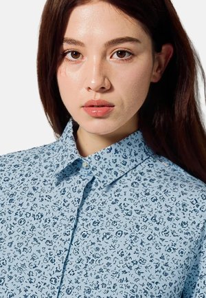 Hellblaues Hemd mit Knopfleiste, verziert mit einem floralem Muster in dunklerem Blau. Klassischer Kragen, glatte Textur und dezente Details überall.