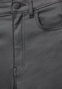 Kadar s crnim kožnim hlačama koje prikazuju prednju džep, petlju za remen i dugme s natpisom "Pull&Bear Od 1991."