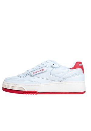 Scarpa da ginnastica bianca Reebok con dettagli rossi, design con lacci e suola in gomma, vista laterale su sfondo bianco.