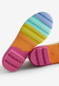 Suole di scarpe in gomma con un motivo a strisce multicolore in blu, verde, giallo, arancione e rosa, dotate di superfici di presa testurizzate.