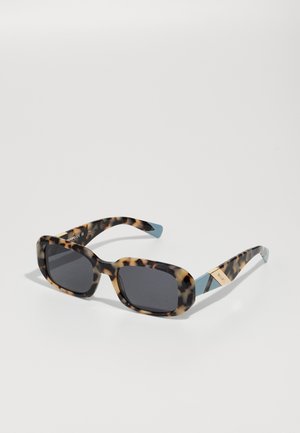 Lunettes de soleil en écaille de tortue avec un design carré, verres gris et accents bleu clair sur les branches. Détail de marque doré présent.