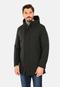 Giacca imbottita nera con cappuccio, chiusura frontale con zip, due tasche laterali e polsini regolabili. Tessuto liscio, design di media lunghezza.