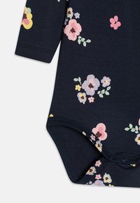 Námornícky dlhý rukáv body s farebnými kvetinovými vzormi v ružovej, žltej a fialovej farbe. Mäkko pružný materiál s patentkami na spodnej časti.