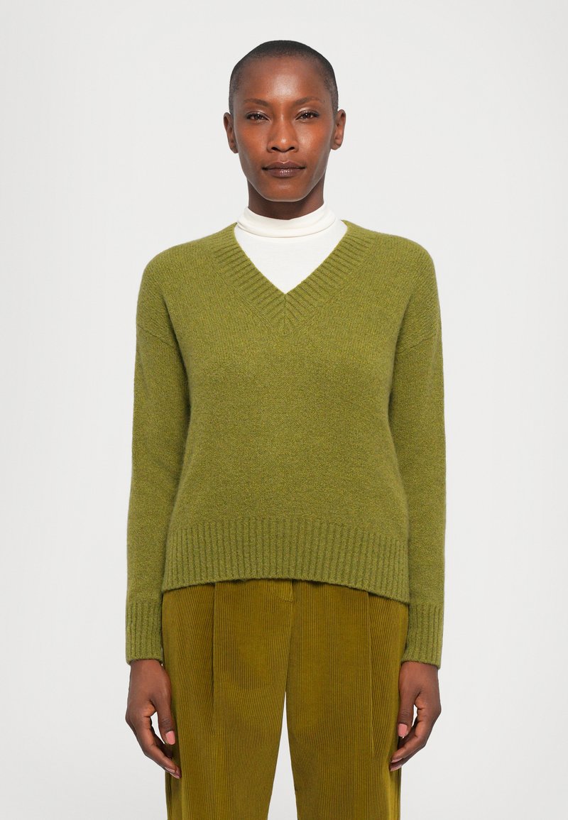 Green v-neck sweater with ribbed hem and cuffs, made of soft material, paired with olive-green corduroy pants. Simple design and textured finish.
