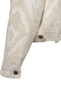 Faux fur crèmekleurige jacket met een zachte, gestructureerde afwerking, voorzien van een knoopdetail bij de manchette. Kenmerkend dierenachtig patroon aanwezig.