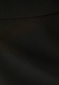 Tissu textile noir, texture lisse avec un subtil éclat, présente un design légèrement drapé et un bord replié le long du haut.