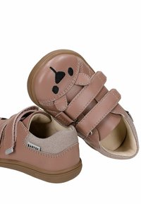 Chaussures pour enfants marron clair avec des bandes Velcro et un motif de visage de chien noir sur le bout, avec une partie talon en tissu et une semelle en caoutchouc.