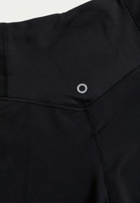 Svart atletisk tyg med en slät textur, som har en framträdande grå logotyp och kontrasterande sömmar, designat för träningskläder.