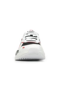Sneaker atletico bianco con accenti neri e rossi, upper testurizzato, sezioni in mesh, lacci e suola in gomma con scanalature per la trazione.