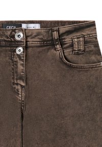 Jean en denim marron avec fermeture à double bouton argenté, poche avant et passants de ceinture visibles sur fond blanc.