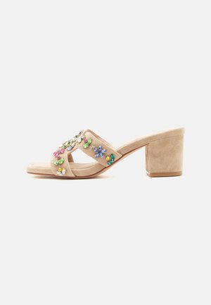 Mule de ante beige con puntera abierta, tacón cuadrado y adorno de pedrería floral multicolor en la correa.