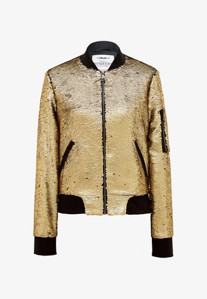 Złota bomberka z cekinów z czarnym prążkowanym kołnierzem i mankietami. Posiada zamek błyskawiczny z przodu oraz boczne kieszenie dla większej funkcjonalności.