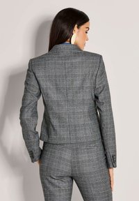 Grijze geruite getailleerde blazer met een stijlvolle pasvorm, enkele knoopsluiting en gestructureerde schouders. Beschikt over een soepel materiaal met een subtiele glans.