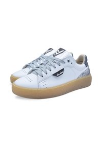 White sneakers with grey laces, a textured gum sole, and metallic accents. Features perforations and a logo on the side.