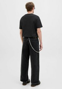 Musthave mustärane T-särk, laia lõikega, koos tumedates hallides laiadest pükstest. Omab hõbedast ketti, mis on kinnitatud selja taha. Minimalistlik disain.