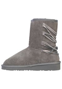 Stivaletto alla caviglia in suede grigio con punta arrotondata, caratterizzato da nastri metallici annodati sul lato. Suola piatta in gomma grigia con battistrada testurizzato.