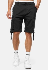 Shorts de carga negros con bolsillos laterales, ajuste estructurado, dobladillos ajustables y cierre de botón. Fabricados en un tejido de algodón duradero.