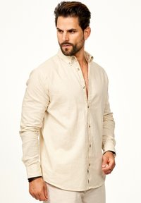 Beige Leinen-Hemd mit Knöpfen, Kragen, langen Ärmeln und Relaxed Fit. Verfügt über Holzknöpfe und einen strukturierten Stoff.