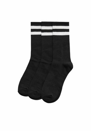 Tres calcetines de tripulación negros con dos rayas horizontales blancas cerca de la parte superior, dispuestos uno al lado del otro sobre un fondo blanco.