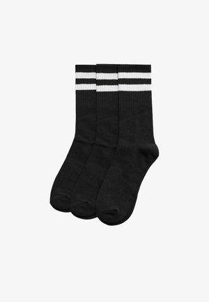 Tres calcetines de tripulación negros con dos rayas horizontales blancas cerca de la parte superior, dispuestos uno al lado del otro sobre un fondo blanco.
