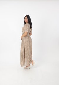 Maxi kjole i lys brun med blomsterprint, korte pufærmer, elastisk talje og matchende åbne hæle med guldhæle.