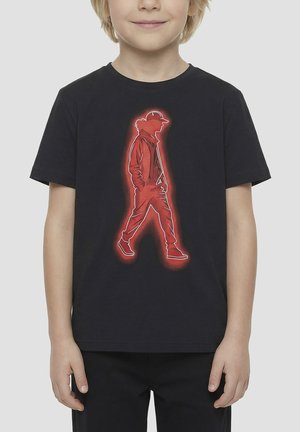 Kind draagt zwart T-shirt met rood neonstijl omlijning van een persoon die loopt, handen in de zakken, met pet en jas.