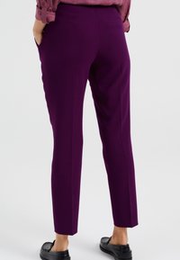 Lila skräddarsydda byxor med smal passform, som har framfickor och en mjuk textur, tillsammans med svarta loafers.