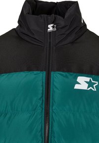 Puffer jacket with black top and teal bottom, featuring a high collar, zip closure, and white logo accent on the chest. Textured material.