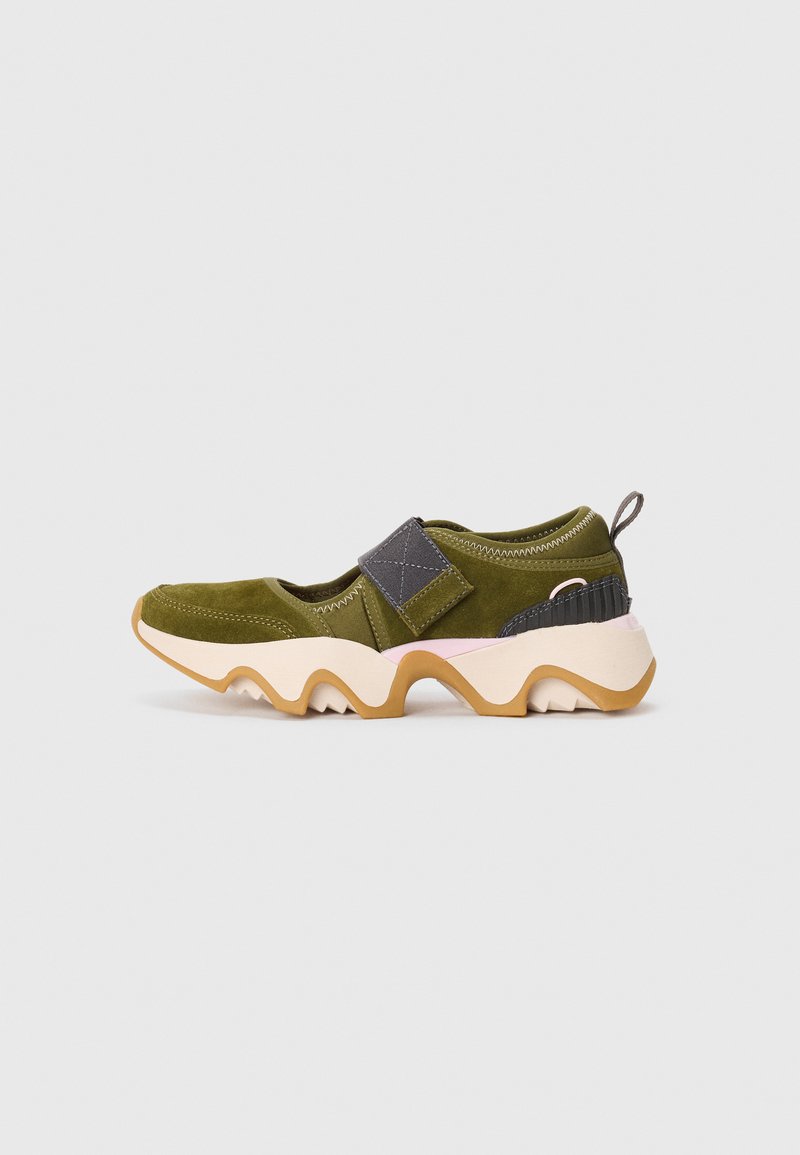 Olive green sporty sneaker with beige wavy sole, gray velcro strap, black and pink accents, and a pull tab on the heel.