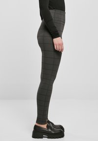 High-waisted, patterned black leggings with a checkered texture, paired with black platform loafers. Side view showcases fit and design.