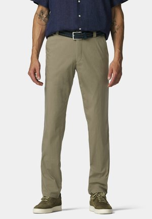 Man draagt beige broek, olijfgroene gevlochten riem, olijfgroene sneakers met witte zolen en een donkerblauw overhemd met knopen.