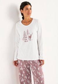 Vit långärmad topp med en ljusrosa skog och hjortgrafik. Kombineras med rosa pyjamasbyxor prydda med vita träd- och hjortmönster.