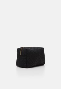Neceser de cosméticos negro acolchado con forma rectangular, que presenta un cierre de cremallera dorada y patrones geométricos en relieve en la superficie.