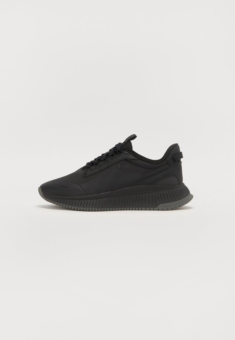 Chaussures de sport noires avec un dessus en mesh, un bout rond et une semelle en caoutchouc texturé. Présentent un profil bas et un design à lacets avec une languette à l'arrière.