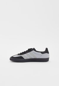 Athletic shoes with a gray mesh upper, black synthetic accents, three horizontal gray stripes, and a textured rubber sole.