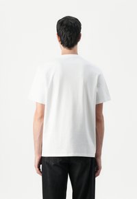 Witte katoenen T-shirt met een ronde hals, korte mouwen en een relaxte pasvorm. De achterkant toont een gladde textuur zonder zichtbare merklogo's of ontwerpen.