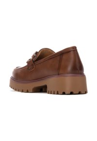 Mocasines de cuero marrón con suela de goma gruesa, con punta redondeada y una correa decorativa en la parte frontal. Parte superior texturizada con detalles de costura.