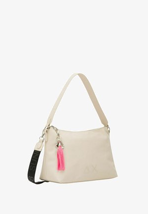Beige synthetische Handtasche mit einem einzigen Tragegurt, ausgestattet mit einem pinken Quasten, silbernen Beschlägen und einem dezent geprägten Logo auf der Vorderseite.