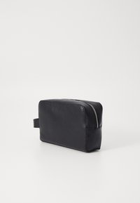 Black leather toiletry bag with a rectangular shape, textured exterior, top zipper closure, and a side handle for easy carrying.
