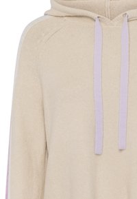 Beige knitted hoodie with a kangaroo pocket, featuring lavender drawstrings and subtle side stripes in pink. Soft texture, relaxed fit.