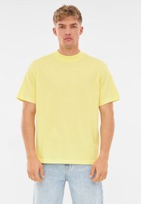 Żółta koszulka z krótkim rękawem i okrągłym dekoltem. Wykonana z bawełny, o luźnym kroju i gładkiej, miękkiej fakturze.