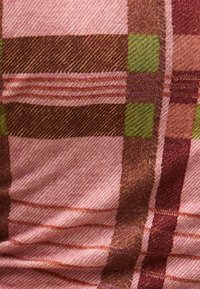 Gewebter Stoff mit einem karierten Muster in Rosa-, Braun- und Grüntönen, mit einer strukturierten Oberfläche und sichtbaren Stickdetails.