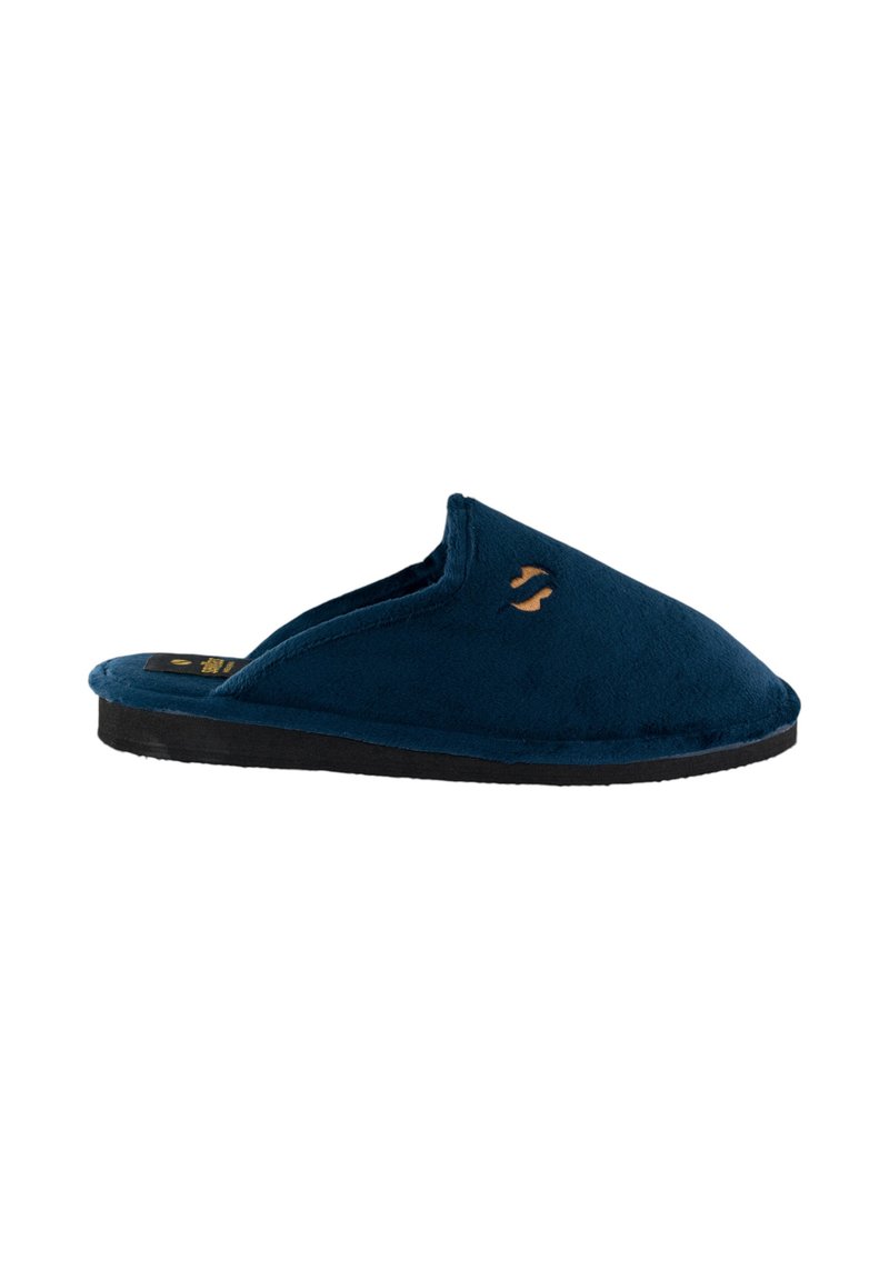 Zapatilla de felpa azul marino con parte trasera abierta, punta redondeada y suela de goma negra. Presenta un pequeño logotipo dorado en el lateral.