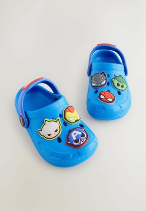Blaue Clogs aus Gummi, mit sechs bunten dekorativen Knöpfen im Superhelden-Design und einem roten Akzent-Riemen. Perforiertes Design für Atmungsaktivität.