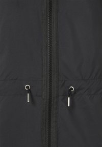Schwarze Jacke mit glatter Textur, ausgestattet mit einem mittigen Reißverschluss, zwei metallischen Ziehflächen und passendem schwarzen Reißverschlussband an der Vorderseite.