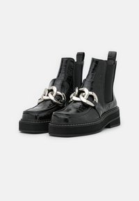 Botines de cuero negro imitación cocodrilo, con detalle de cadena plateada, paneles laterales elásticos y una gruesa suela de goma negra.