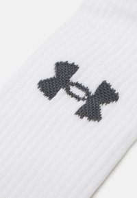 Valge sport sock, millel on hall Under Armouri logo, ribakujuline tekstuur ja tavaline meeskonna pikkuse disain.