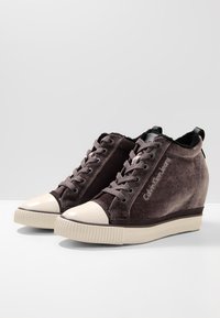 Wedge-Sneaker mit einem Obermaterial aus dunkelgrauem Wildleder, einer hellgrauen Gummi-Zehenkappe und einer strukturierten Sohle. Verfügt über eine Schnürung und eine Markenkennzeichnung.
