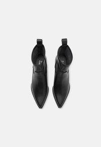 Bocanci din piele neagră până la gleznă, cu vârf ascuțit, textură netedă, margini rotunjite, bandă de tragere la spate și un design minimalist.