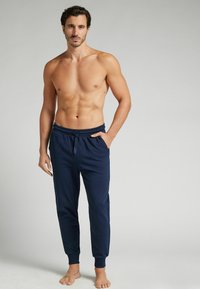 Marineblauwe joggers met een elastische tailleband en zijzakken, voorzien van ribgebreide manchetten en een zachte stoftextuur.